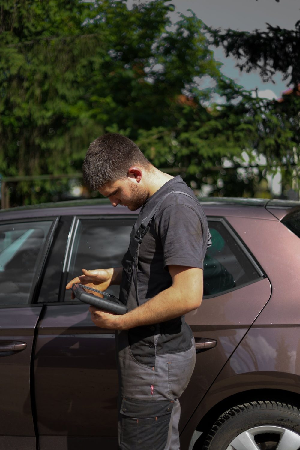 Майстер з діагностичним планшетом біля авто